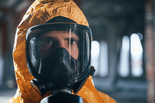 Portrait of man dressed in chemical protection suit that is in the ruins of the post apocalyptic building