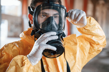 Wearing the respirator. Man dressed in chemical protection suit in the ruins of the post...