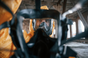 View through the respirator. Man dressed in chemical protection suit in the ruins of the post...
