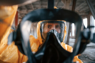First person view through respirator. Man dressed in chemical protection suit in the ruins of the...