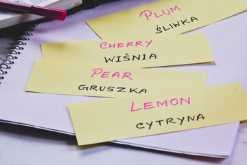 Learning Polish with fruits name on flash card; English to Polish language translation. Selective focus.