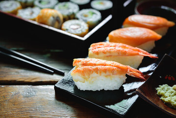 Sushi Set nigiri shrimp and salmon and sushi california rolls with avocado and maki with carrot, on wood,top view