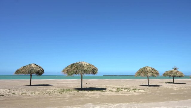 Amazing seascape of an empty tropical beach with thatched parasols. Calm relaxing atmosphere