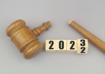 Broken judge gavel and flipping numbers 2022 and 2023 on gray background. Lawlessness and injustice...