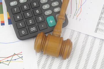 Wooden judge gavel and calculator on financial data. Arbitration and audition concept.