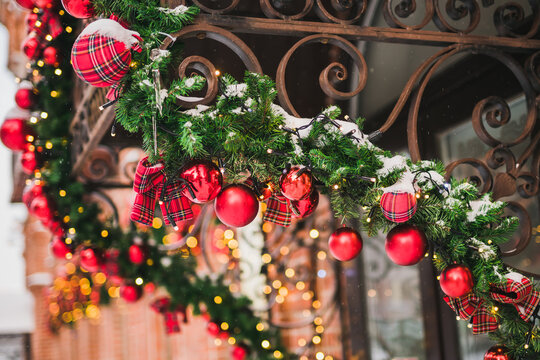 Building front decorated to Christmas with christmas trees fir branches, decorations and garland lights - festive and winter holidays concept