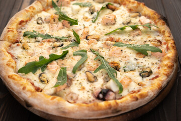 Seafood Italian Pizza with arugula on wooden table.