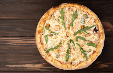 Seafood Italian Pizza with arugula on wooden table.