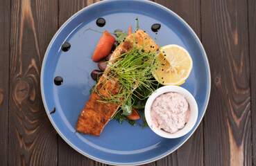 Grilled Salmon with lemon, sauce and fresh tomatoes, top view.