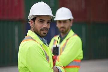 Dock worker man in safety vest work in container port terminal. male Industrial Engineer in Hard Hat, High-Visibility Vest Working. Inspector or Safety Supervisor in Container Terminal. shipping yard.