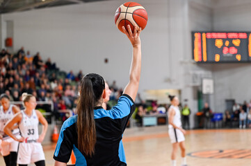 Woman referee keeps the ball during basketball match.