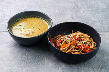 Lunch noodles with pork, sweet pepper and spices and ramen soup with coconut milk, chicken and curry