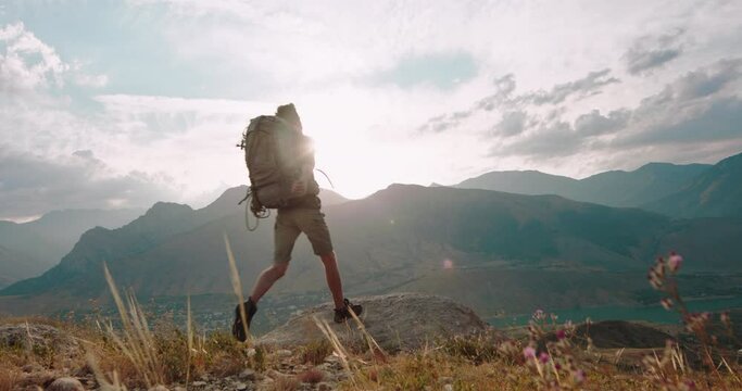 a happy person runs up to the top of the mountain and throws his arms up in the air from a sense of joy and success. Achieving the goal. Become independent. Indescribable emotions