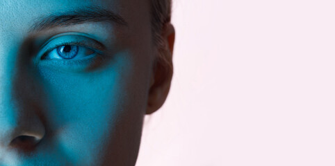 Close up view of blue eye with futuristic holographic interface to display data. Portrait of beautiful young woman, half of face. Augmented reality, future technology, internet concept.