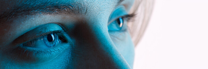 Close up view of blue eye with futuristic holographic interface to display data. Portrait of beautiful young woman, half of face. Augmented reality, future technology, internet concept.