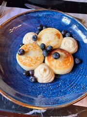 Pancakes with cottage cheese syrniki and cottage cheese fritters with fresh blueberries and sour cream on plate