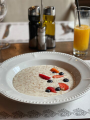 Plate of oatmeal with strawberries and blueberries and a glass of fresh juice