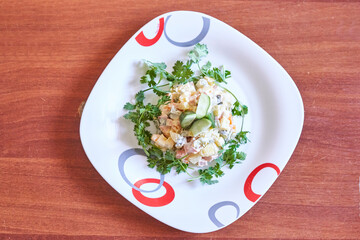 a salad on a white plate with red, blue and gray circles around the plate there is a fork next to it