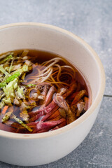 Ramen broth with beef, iceberg lettuce, noodles in a bowl, closeup.