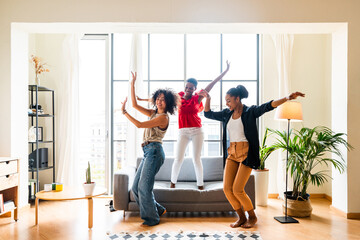 Three mixed race hispanic and black women bonding at home - Multiracial group of happy young female adults spending time together and having fun