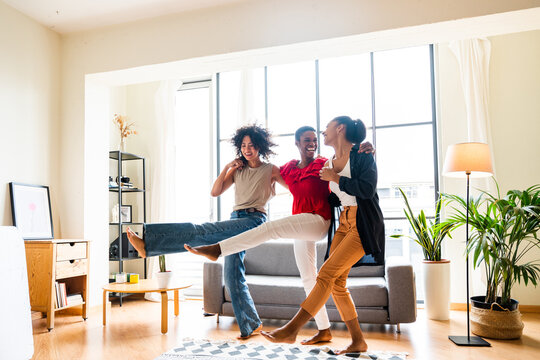Three mixed race hispanic and black women bonding at home - Multiracial group of happy young female adults spending time together and having fun