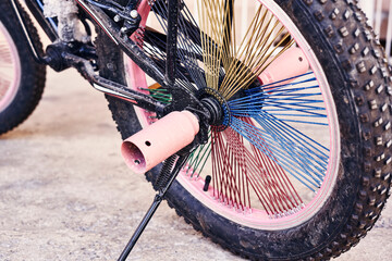 a pink bike with spikes on it's spokes and wheel hubs that are stuck to the rim