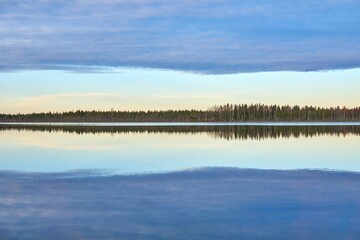 Beautiful landscape of a lake with calm waters that reflect the trees and clouds