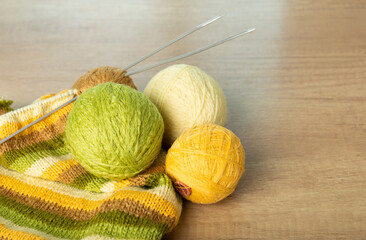 Yarn in warm autumn tones. Cozy homely atmosphere. Women's hobby knitting. Different shades of yellow and green thread colors. Hobby. Knitting accessories.
