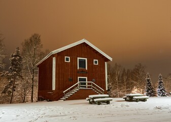 Exterior view of an old farmhouse covered in white snow during winter in the evening