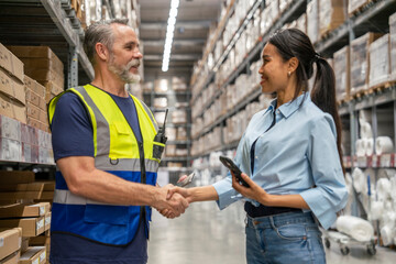 middle-aged chief clerk shakes hands with Asian female customers to introduce themselves and welcomes them to manage deliveries in wholesale stores and warehouses.