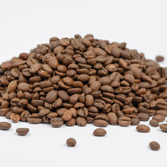 A pile of coffee beans on a white background, place for advertising.