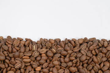 Coffee beans laid out in one wide row on a white background, place for inscription and advertising.
