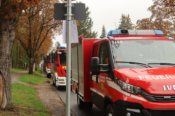 Many Fire Brigade Cars in a row with a street and Autumnal trees