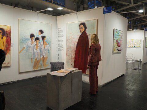 Artist Karina Laru-Nau in a suit looking at her paintings during an art fair in Frankfurt, Germany