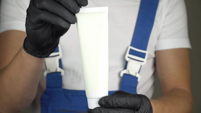 Employee in blue uniform and white T-shirt holds white tube on which you can place logo or text. Space for copying.