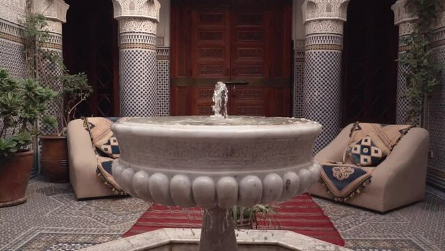 Riad interior showing a stone marble fountain in slow motion footage.