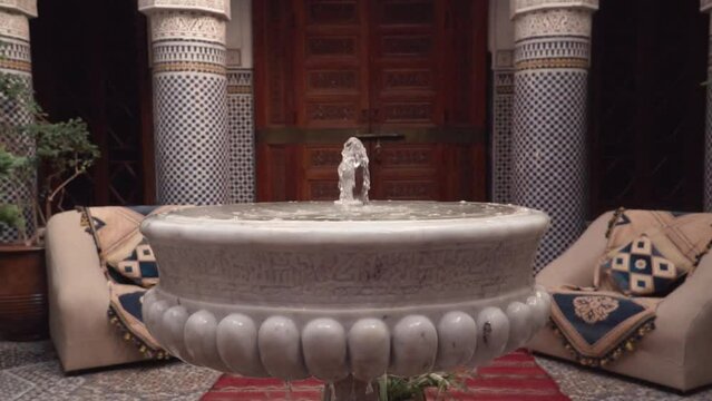 Riad interior showing a stone marble fountain close up in slow motion footage.