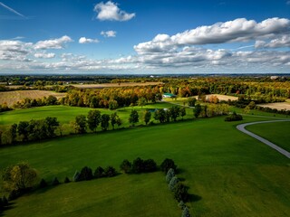 Aerial shot of a field surrounded by trees during the daytime under a blue sky in Auburn New York