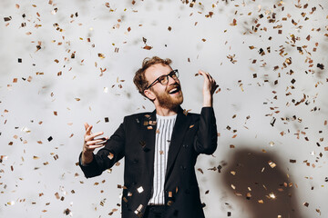 Celebration time. Portrait of a happy guy dancing under glittering confetti.