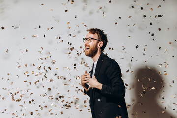 Celebration time. Portrait of a happy guy dancing under glittering confetti.