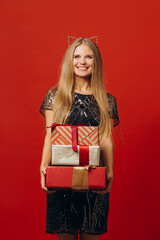 Merry Christmas: a Happy Blonde Woman in a Festive Dress Holding Christmas Presents. Portrait - stock photo..