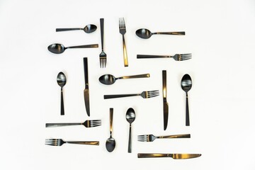Overhead shot of black metal forks and spoons on a white background