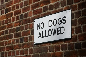 "No dogs allowed" sign on the brick wall
