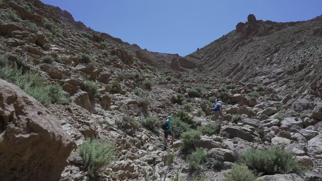 Low-angle shot of a people hiking through the rocky trail of the Todra gorge, Morocco