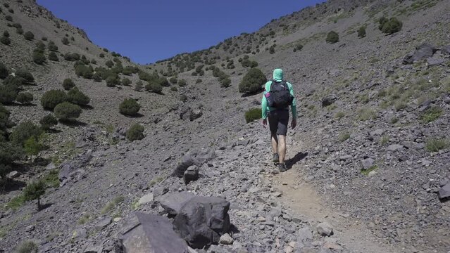 Low-angle shot of a man hiking through the rocky trail of Imlil, Morocco