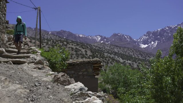 Low-angle shot of a man hiking through the trail of Imlil, Morocco