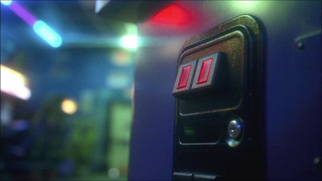 Man sliding a coin into the acceptor and playing an arcade game on the machine