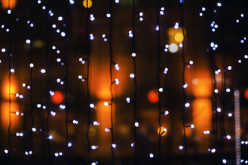 Fototapeta na wymiar City lights defocused. Selective focus on Christmas decorations illuminated at night. Merry Christmas and Happy New Year card or banner with copy space