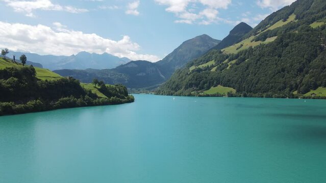 Aerial of the mesmerizing turquoise lake Lungern surrounded by green mountains in Switzerland