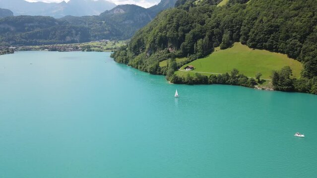 Aerial of boat on voyage on the turquoise lake Lungern surrounded by green mountains in Switzerland
